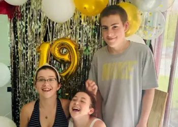 15-year-old Malakye stands with his two sisters at a birthday party