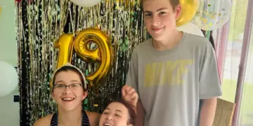 15-year-old Malakye stands with his two sisters at a birthday party