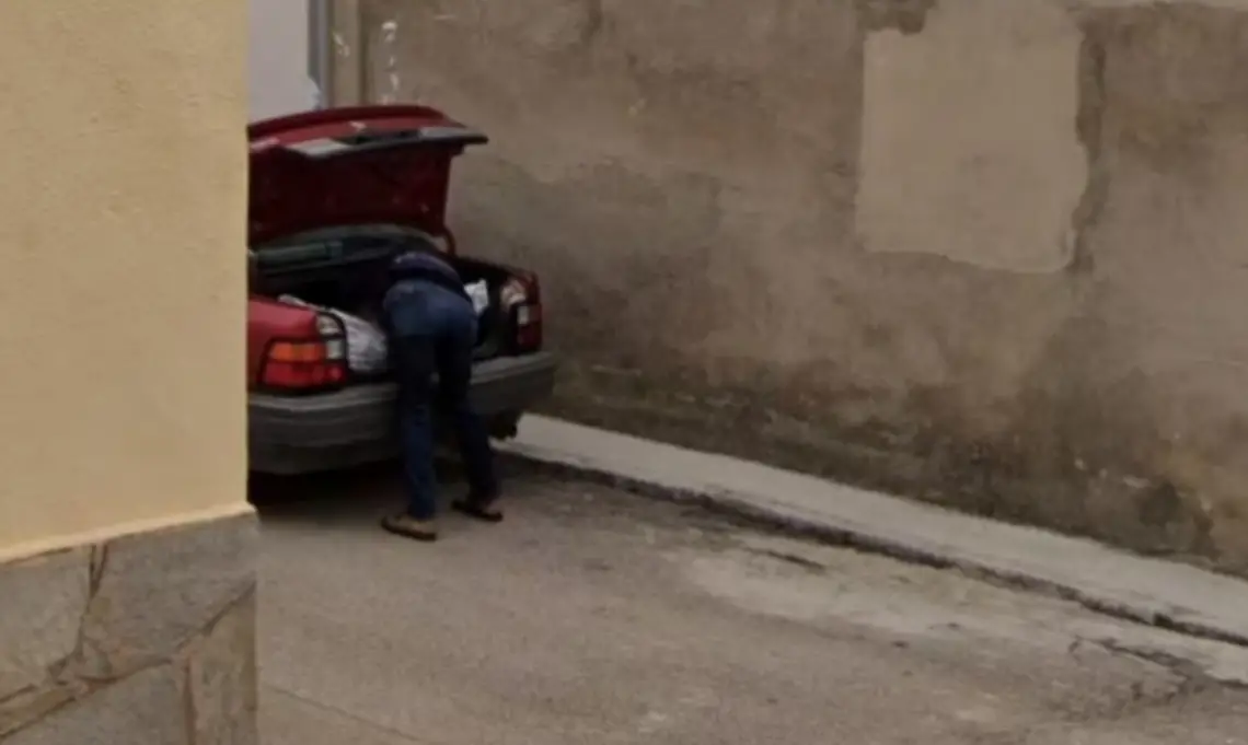 A picture, which Spanish police used as part of a missing person investigation, shows a man placing what appears to be a bag with a body in a car's trunk, in Tajueco, Spain, dated October 2024 (Courtesy Google Street View/Handout via REUTERS)