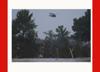 A helicopter flies over the Guadalupe River after a flash flood swept through the area, Friday, July 4, 2025, in Kerrville, Texas. (AP Photo/Eric Gay)