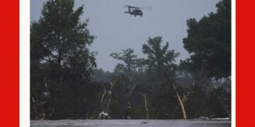A helicopter flies over the Guadalupe River after a flash flood swept through the area, Friday, July 4, 2025, in Kerrville, Texas. (AP Photo/Eric Gay)